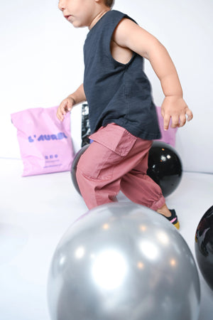 Child model of Little Aurel in dusty pink pants, playing with balloons on a white background