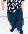 Child wearing a black t-shirt with white dinosaur prints and black pants on a white background