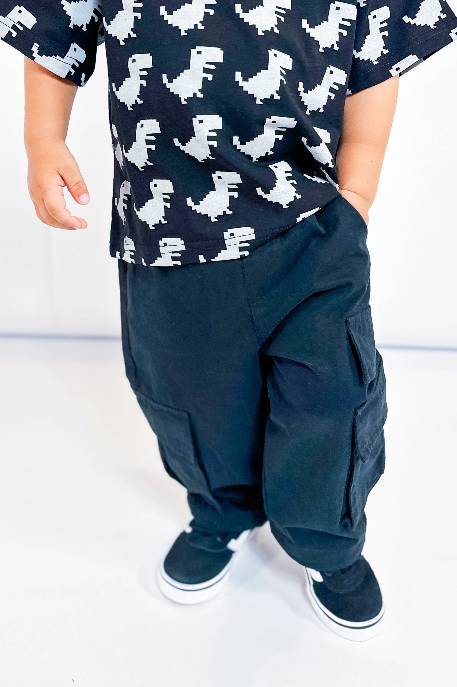 Child wearing a black t-shirt with white dinosaur prints and black pants on a white background