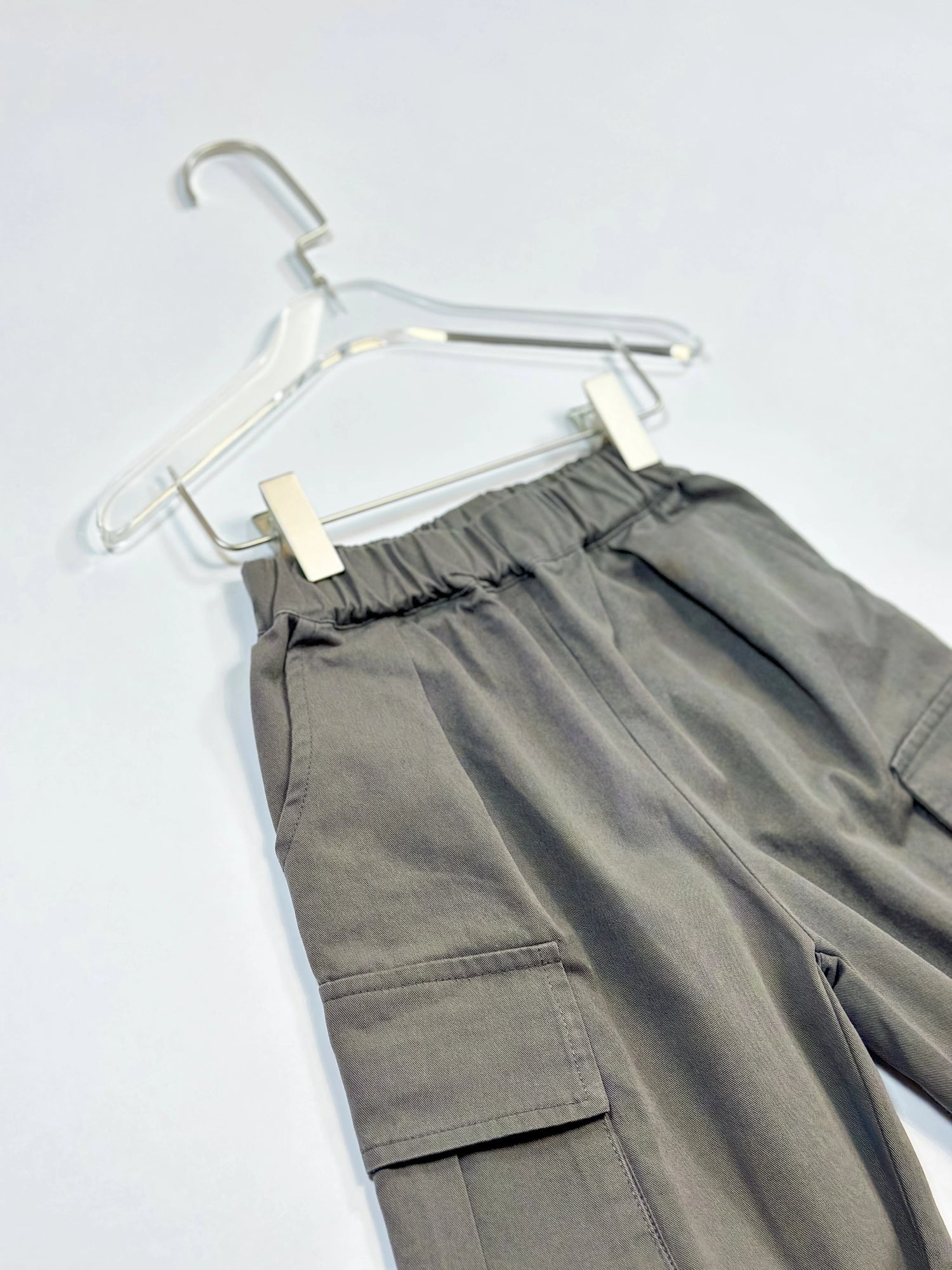 cargo pants on hanger close-up elastic waistband on white background – practical and stylish streetwear by Little Aurel