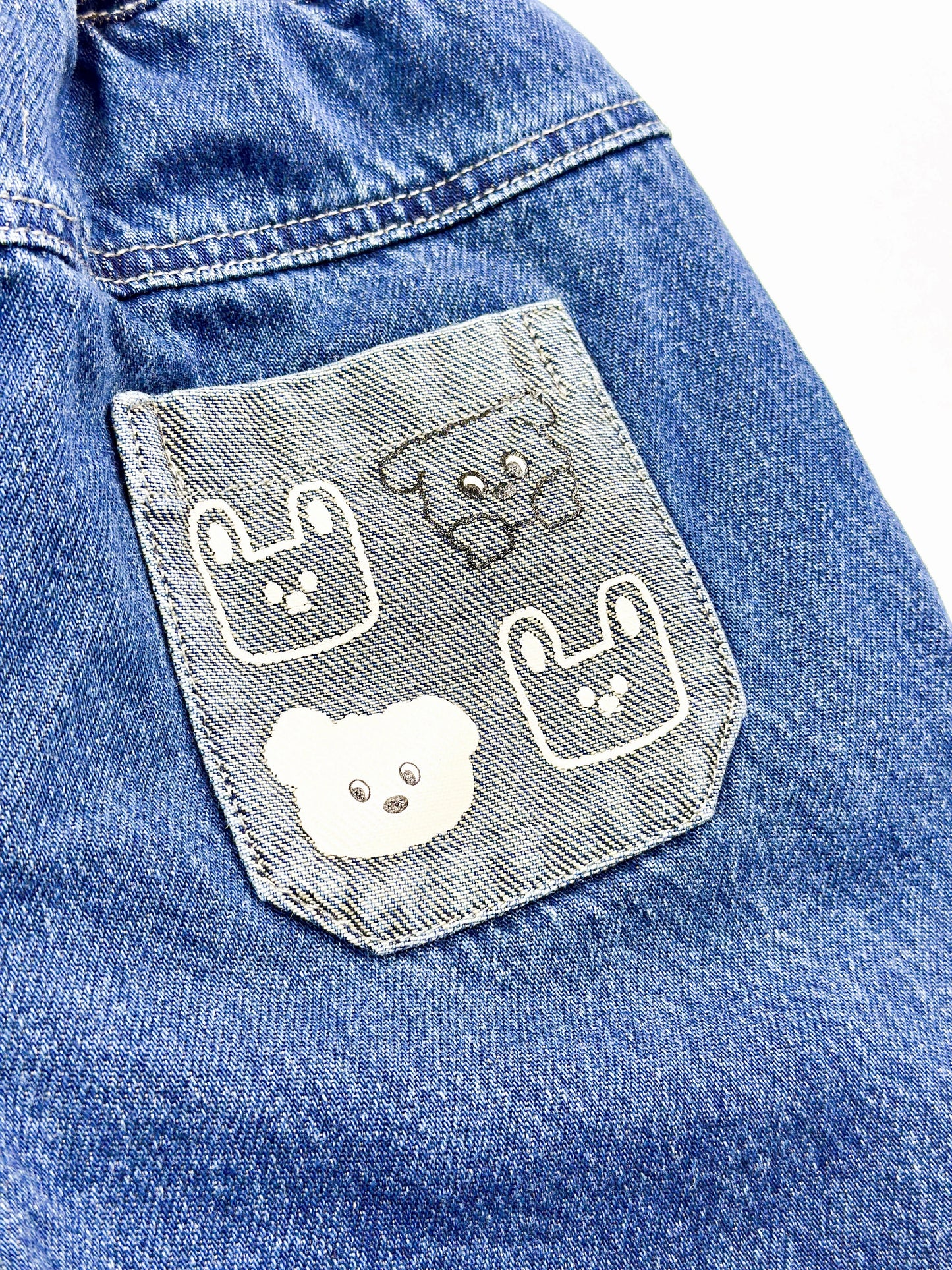 Blue denim jacket with embroidered dog faces on a pocket


