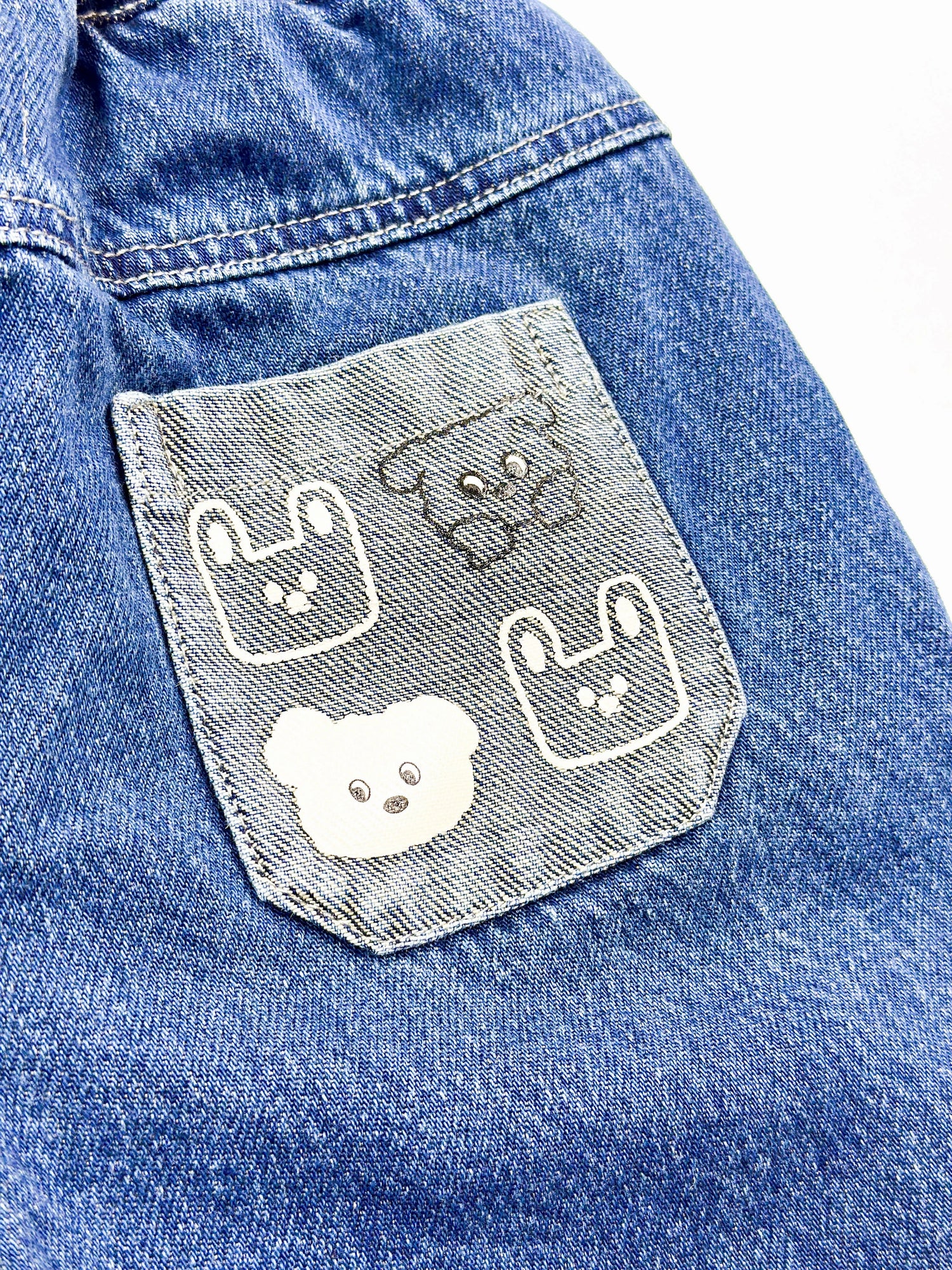 Blue denim jacket with embroidered dog faces on a pocket

