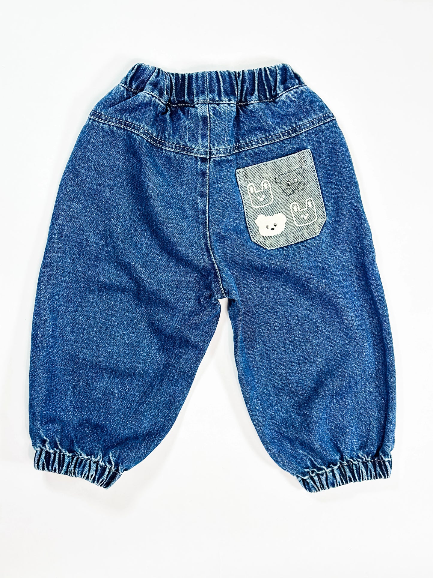 Blue denim baby pants with a decorative pocket on a white background