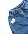 Close-up of blue denim pants with a brand tag on a white background