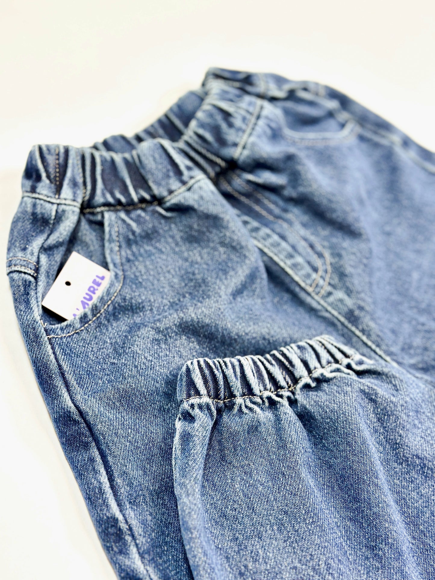 Blue baggy jeans with a visible brand tag on a light background