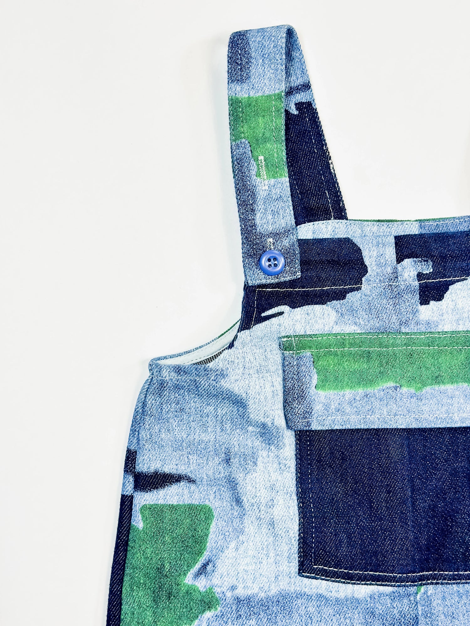Close-up of a denim apron with green and blue patterns on a white background by Laurel