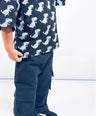 Child wearing a black Little Aurel t-shirt with dinosaur pattern and black cargo pants on a white background