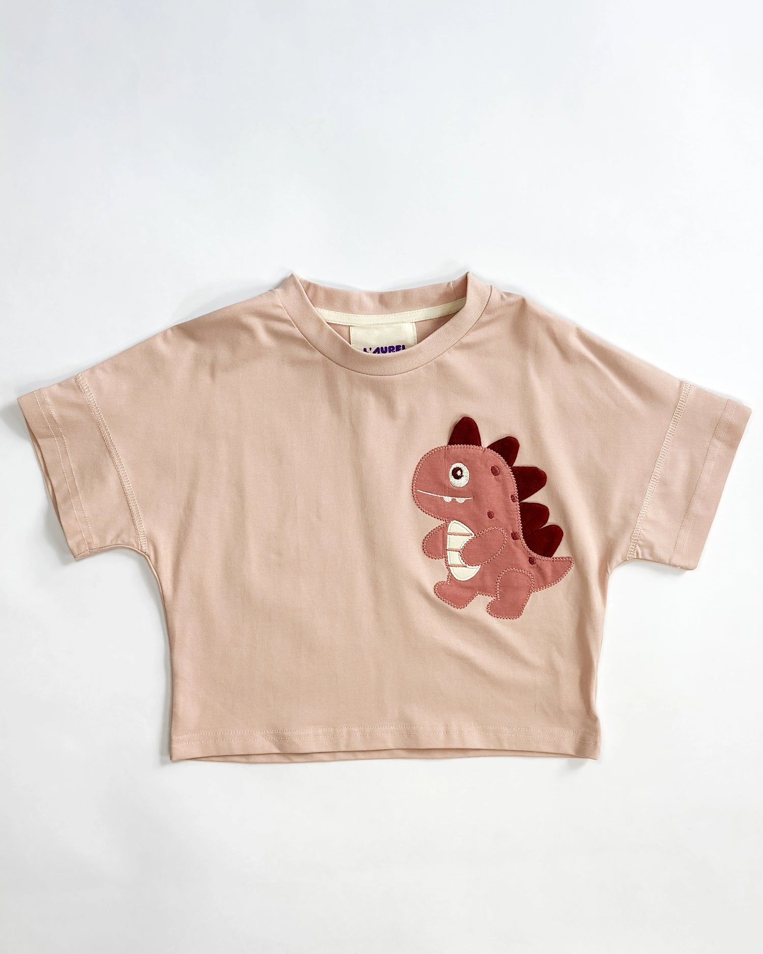 pink t-shirt with a dinosaur patch on a white background by L'aurel
