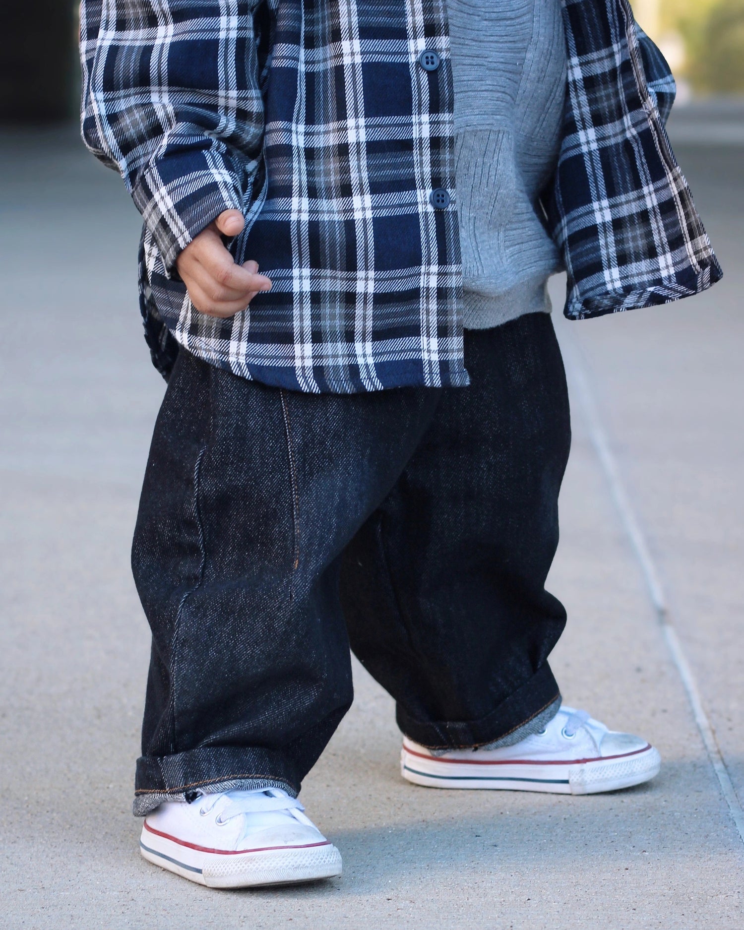 Little Aurel Model with plaid blouse shirt, knit sweater in gray and baggy barrel jeans in black.