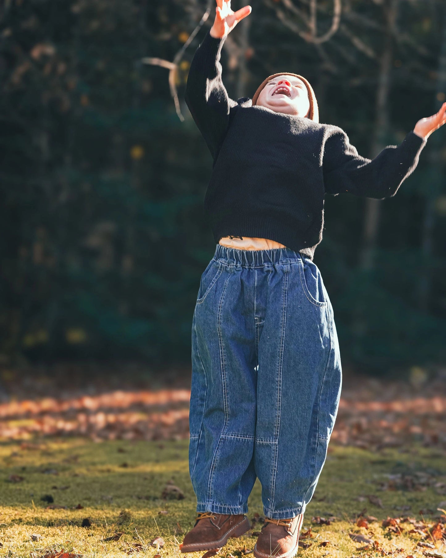 Black knit pullover for toddler boys with cream neckline and Blue signature jeans by Little Aurel.