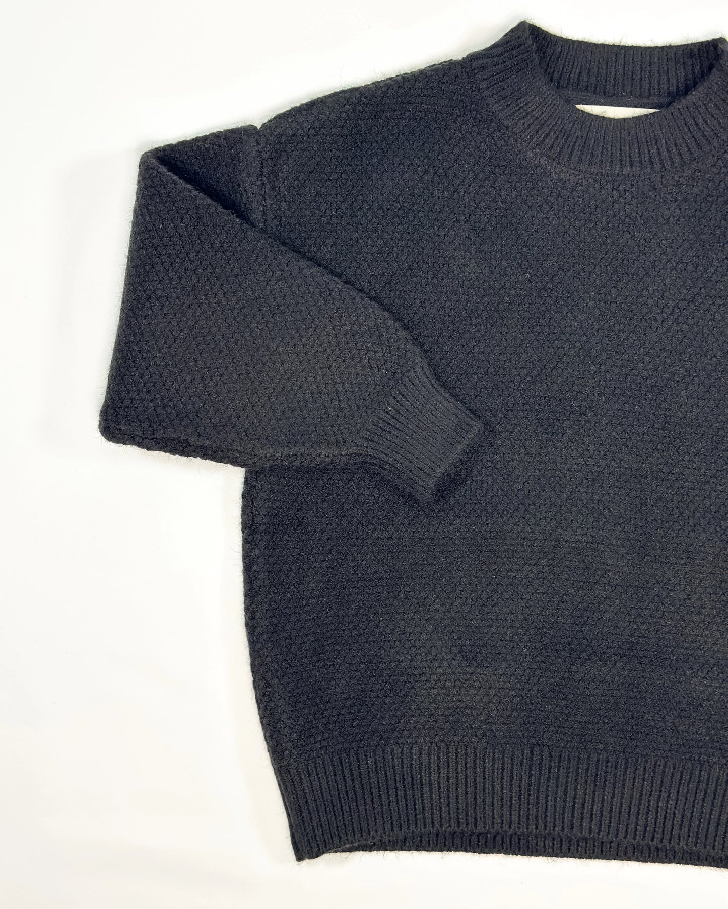 Black knit pullover for toddler boys with cream neckline and cuffs by Little Aurel.