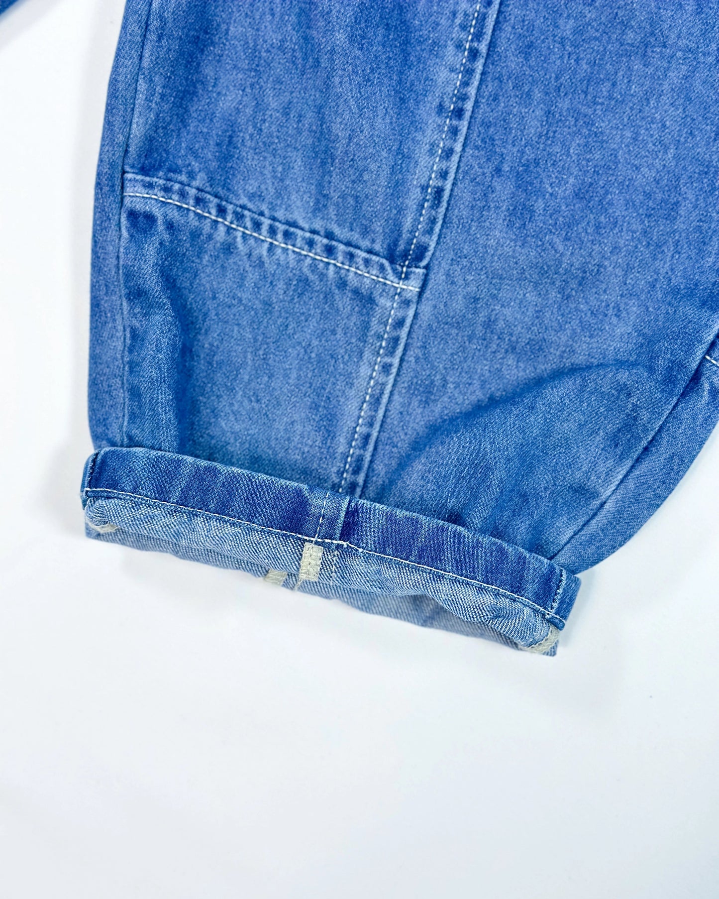 Close-up of a rolled-up blue denim sleeve on a white background