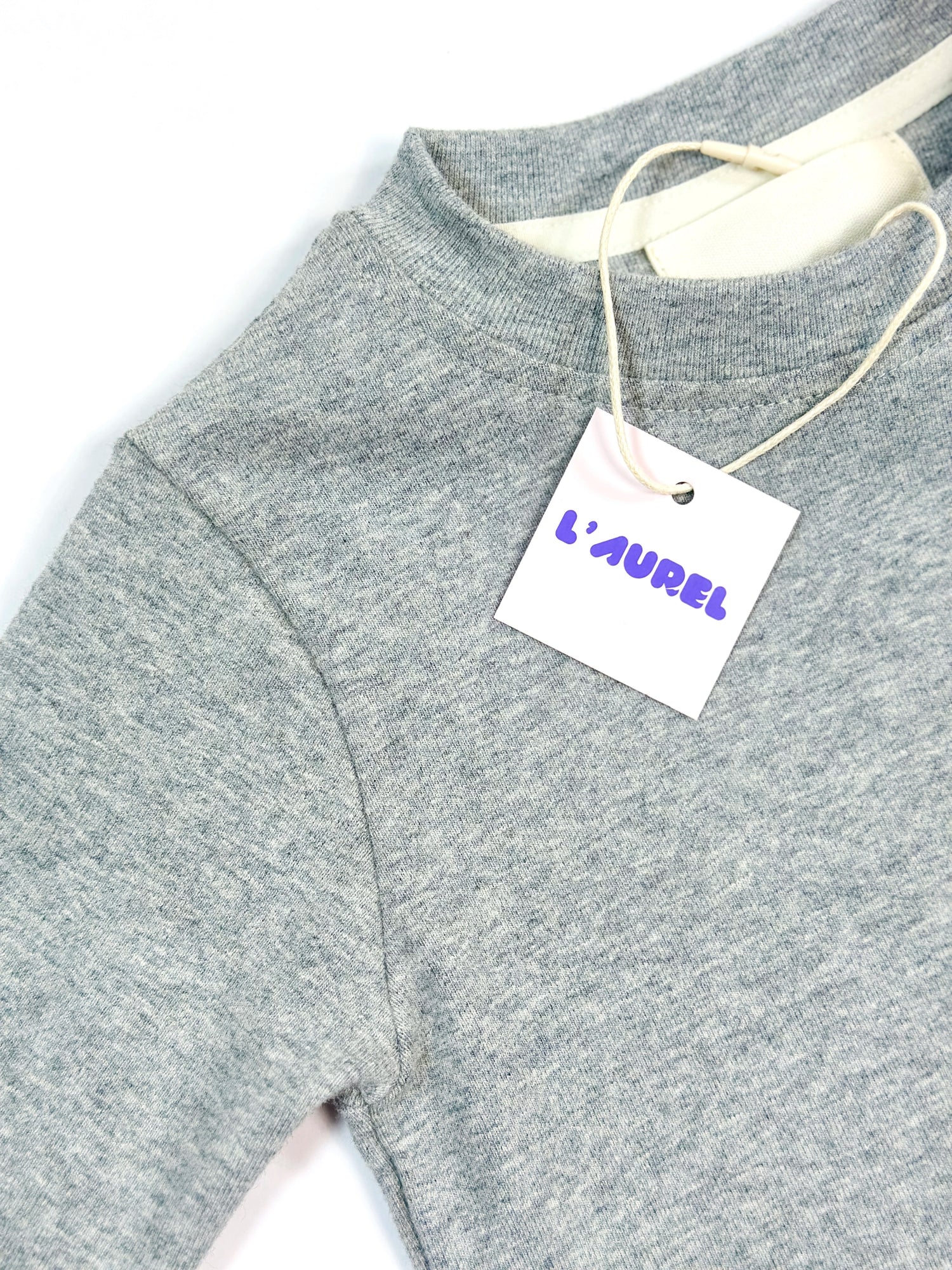 Gray sweater with a 'L'Aurel' tag on a white background