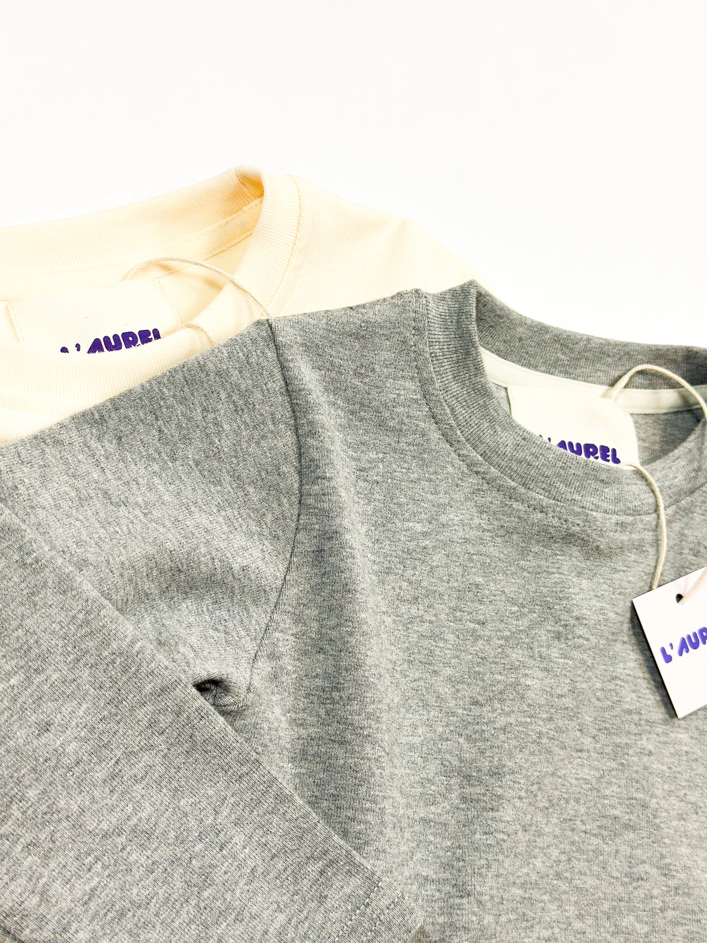 Gray and creme longsleeve shirt with a tag on a white background by L'aurel