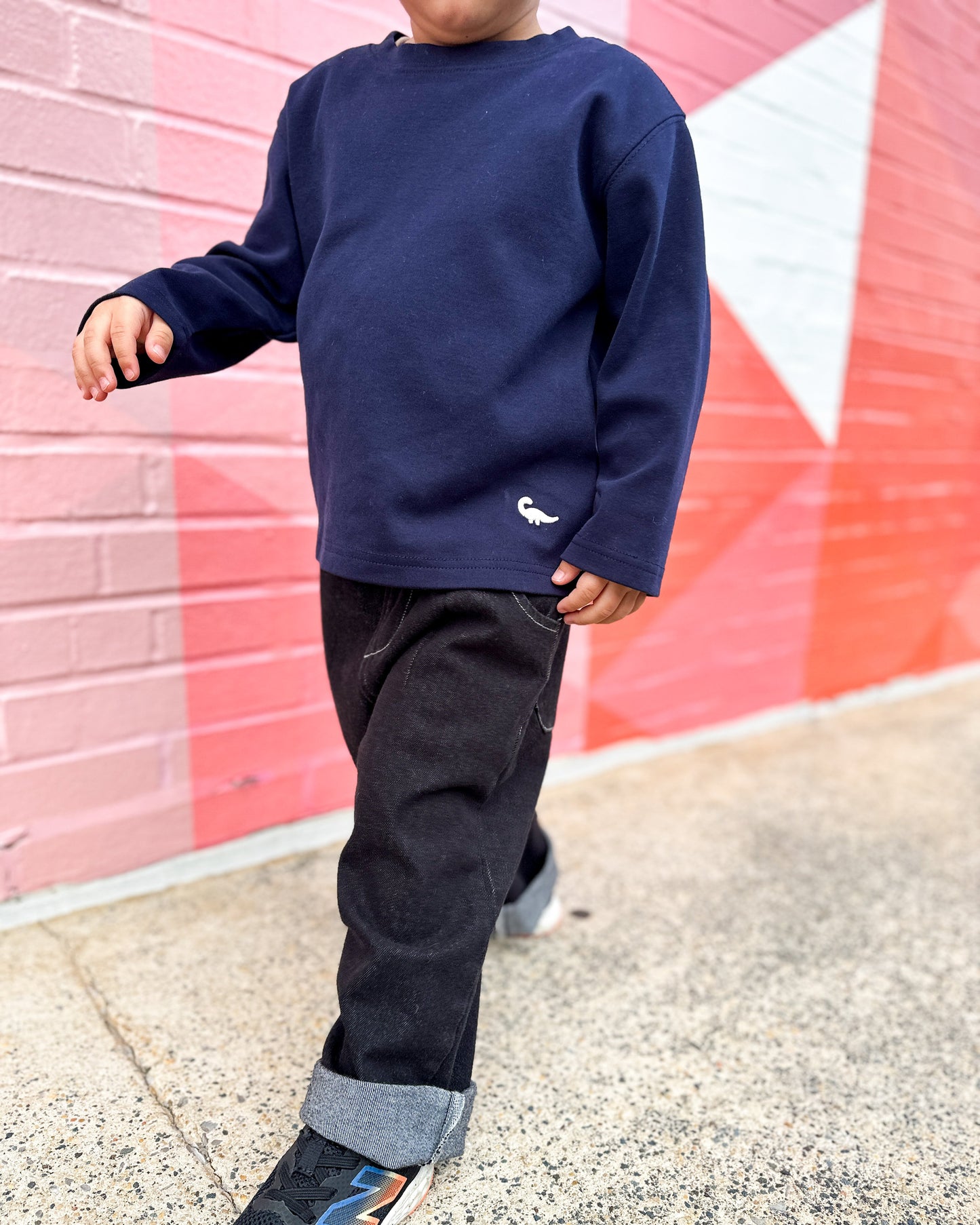 Model wearing Loose-fit longsleeve shirt for kids in navy blue with small dinosaur embroidery