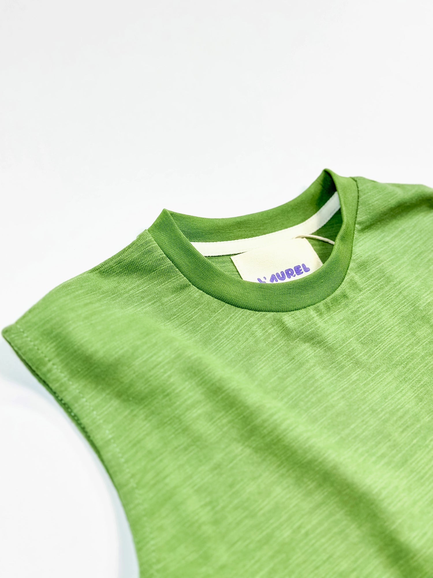 Green sleeveless shirt with a brand label on a white background by L'aurel