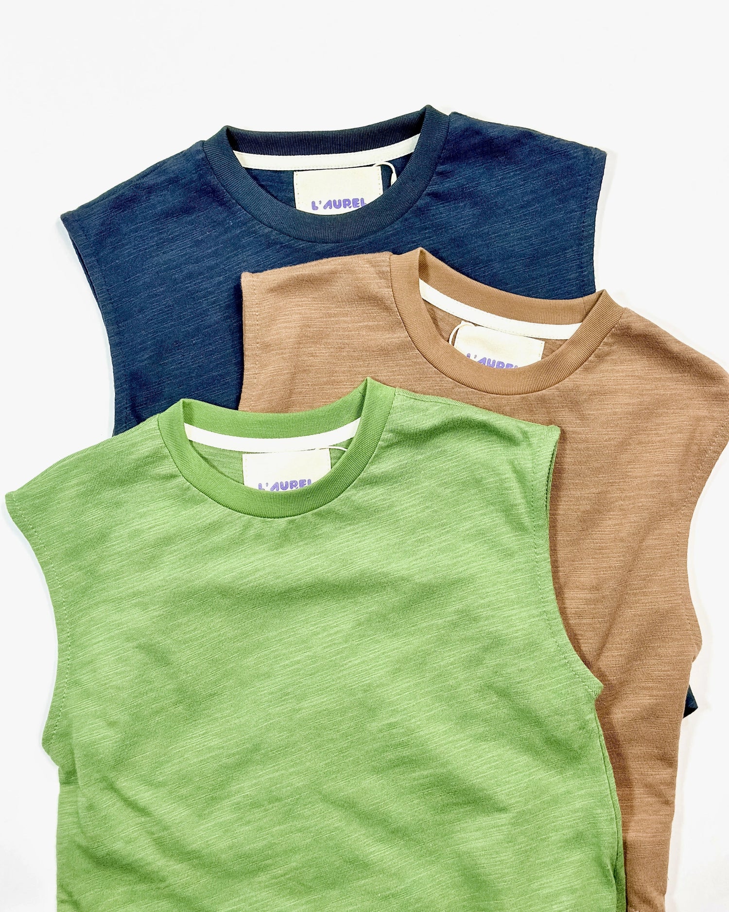 Three sleeveless shirts in green, blue, and brown on a white background by L'aurel