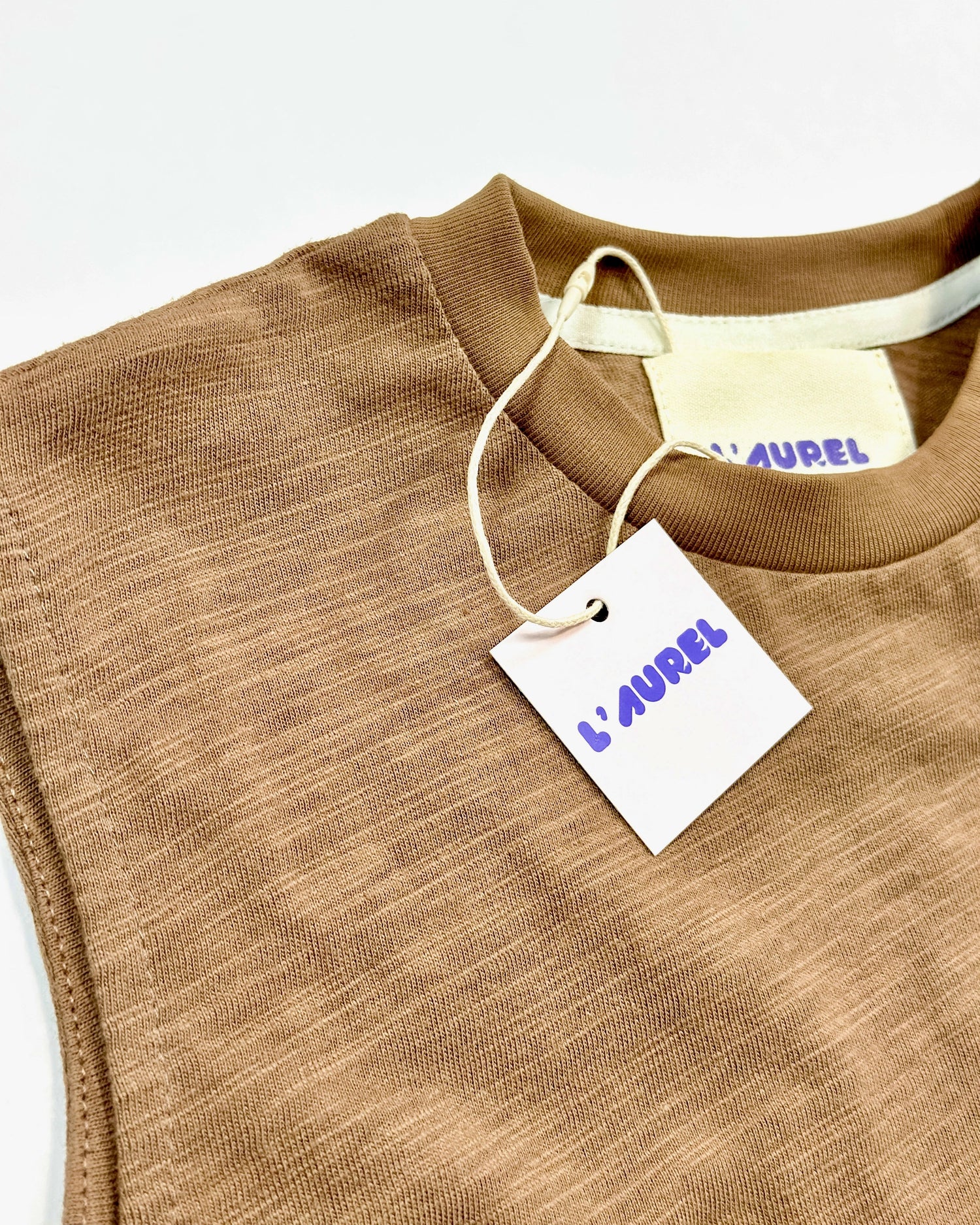 Brown garment with a 'L'Aurel' tag on a white background